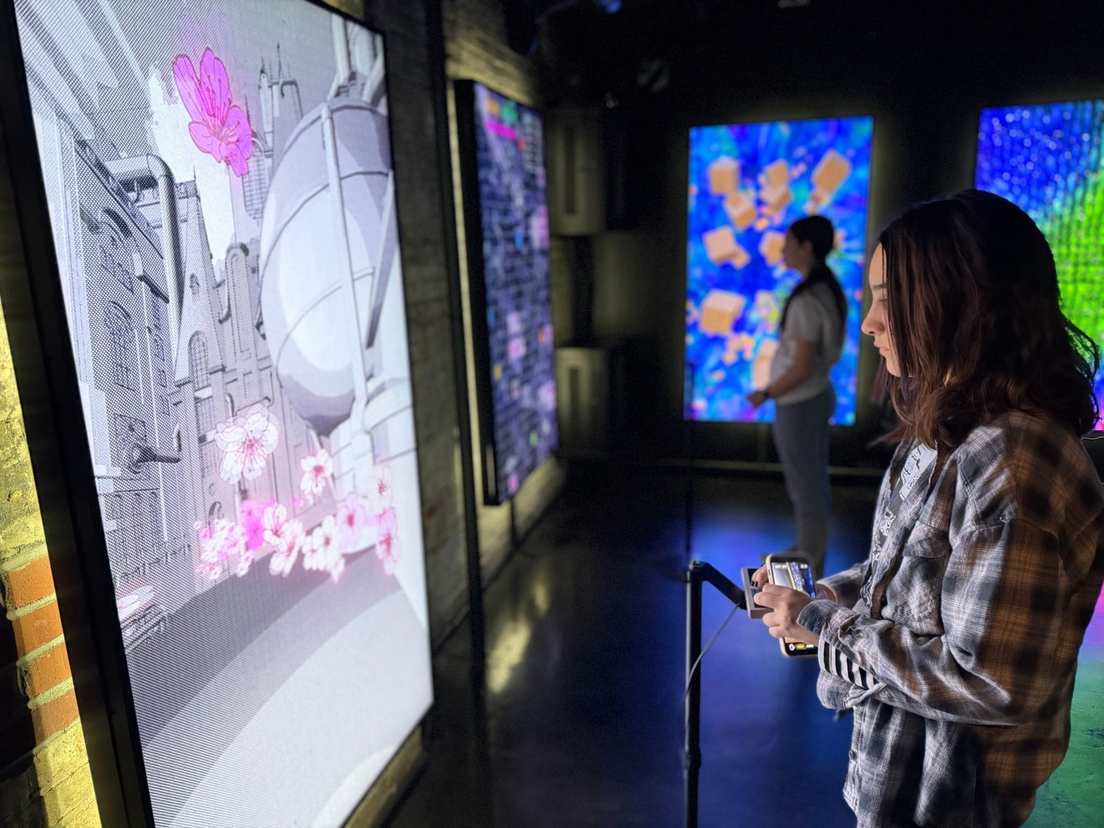 Kiddos holding an NES controller while playing an interactive cherry blossom and city game on a mezzanine screen, with other reactive installations visible in the background